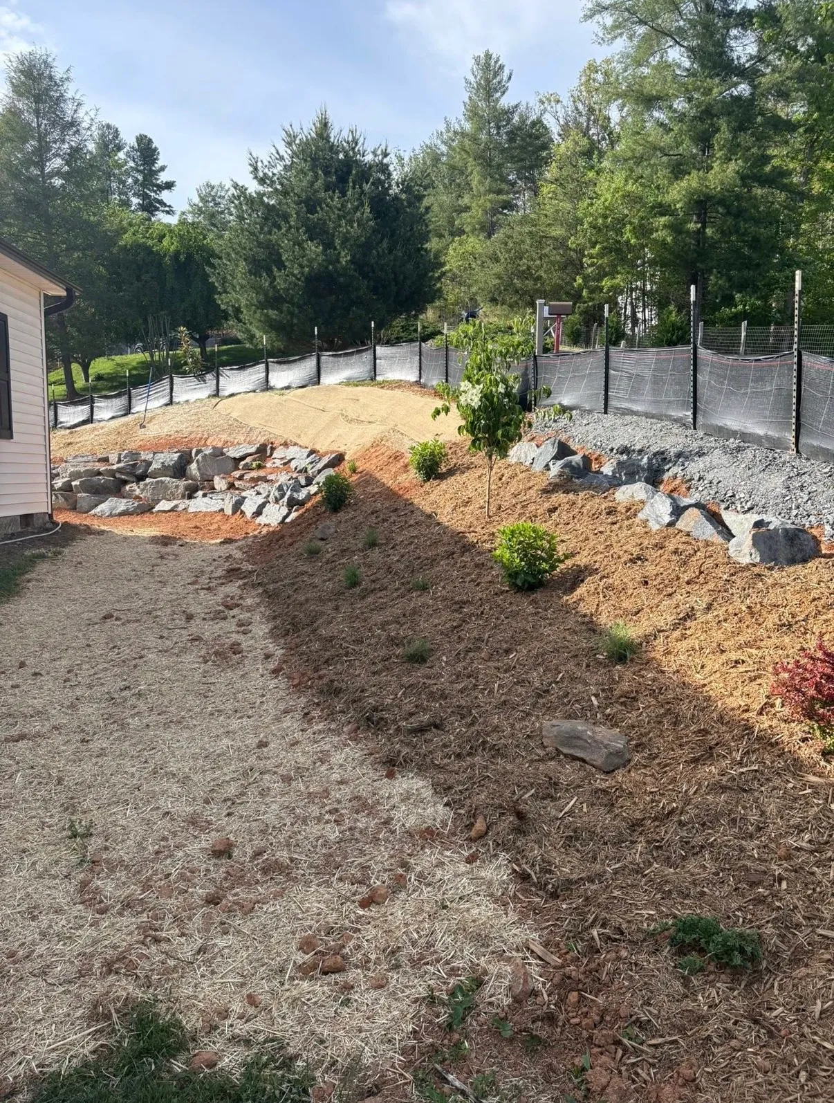 Natural boulder retaining wall finished with mulched plantings on a residential WNC slope